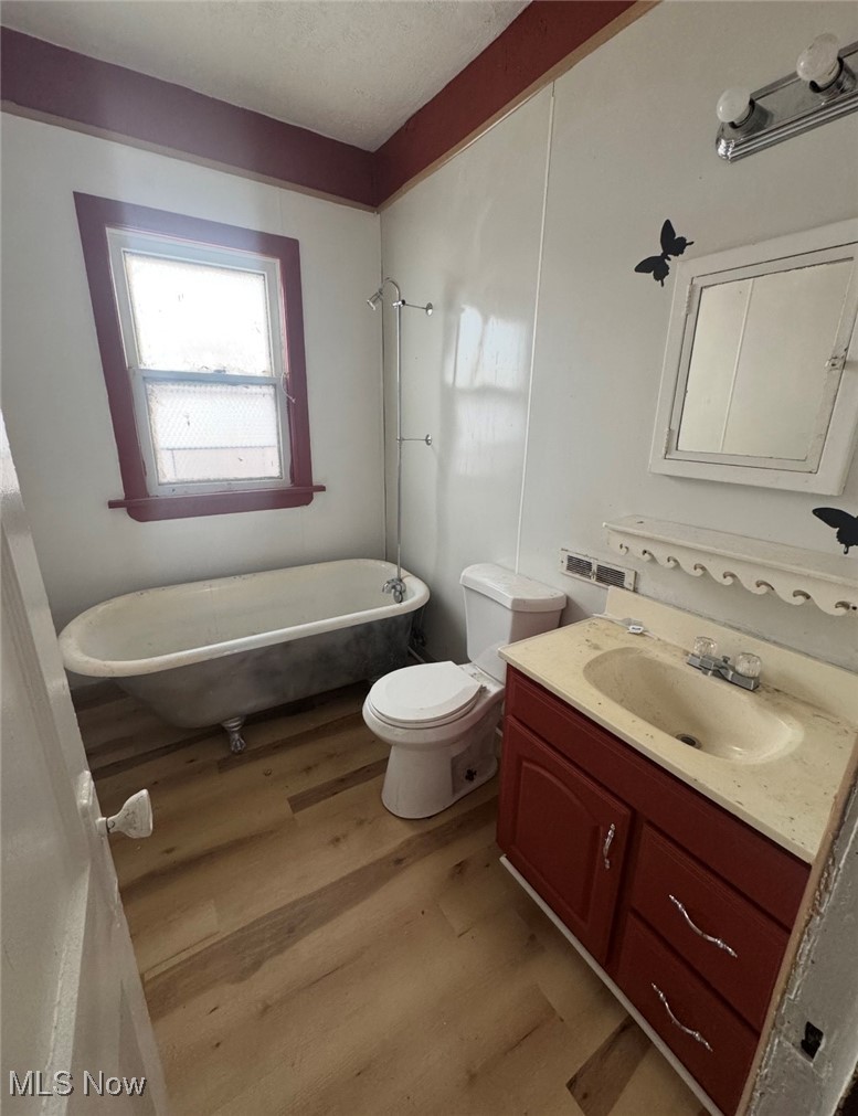 12406 Kinsman Road Cleveland, OH 44120 - Photo 10 of 29 Full bathroom featuring a soaking tub, vanity, light wood-style floors, and a textured ceiling