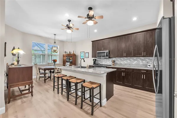 a kitchen with kitchen island granite countertop a table chairs a sink dishwasher refrigerator and cabinets