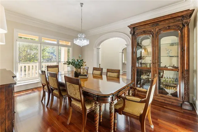 a kitchen with stainless steel appliances granite countertop a stove top oven a sink a dining table and chairs with wooden floor