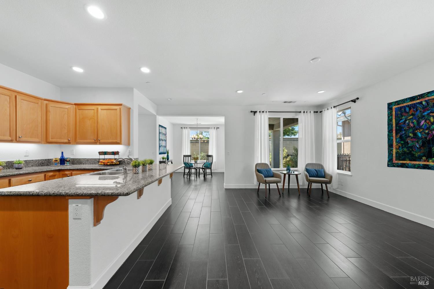 living room, dining room, and kitchen,  all with gleaming wood-look tile floors