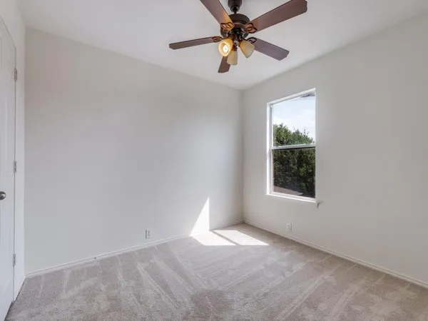 an empty room with a window and a fan