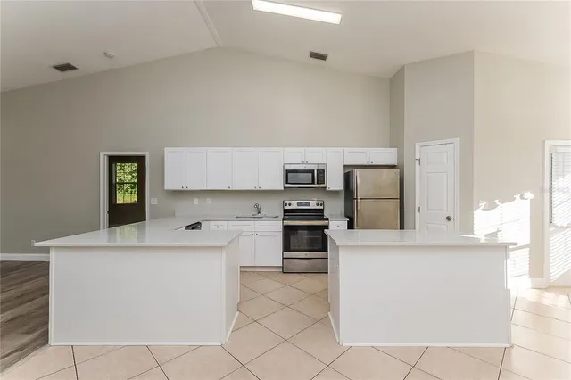 a kitchen with stainless steel appliances a stove a sink and white cabinets