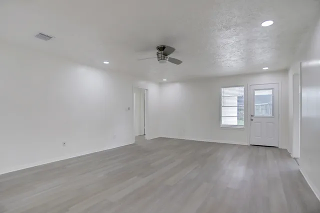 an empty room with wooden floor and windows