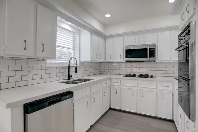 a kitchen with white cabinets a sink and appliances