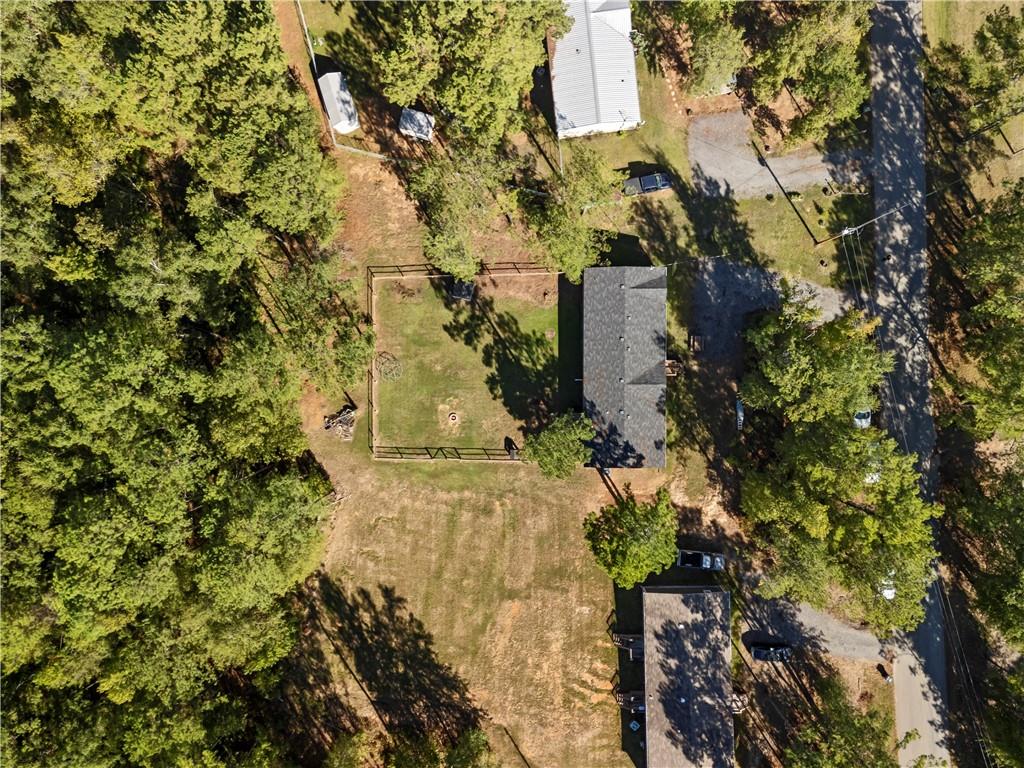 89 Ridge Road Seale, AL 36875 - Photo 43 of 46 Expansive property featuring a dark-shingle roof, gravel drive, and a fenced pasture area, surrounded by mature trees