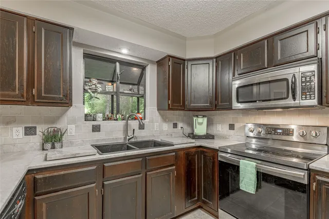 a kitchen with stainless steel appliances granite countertop a sink stove and microwave