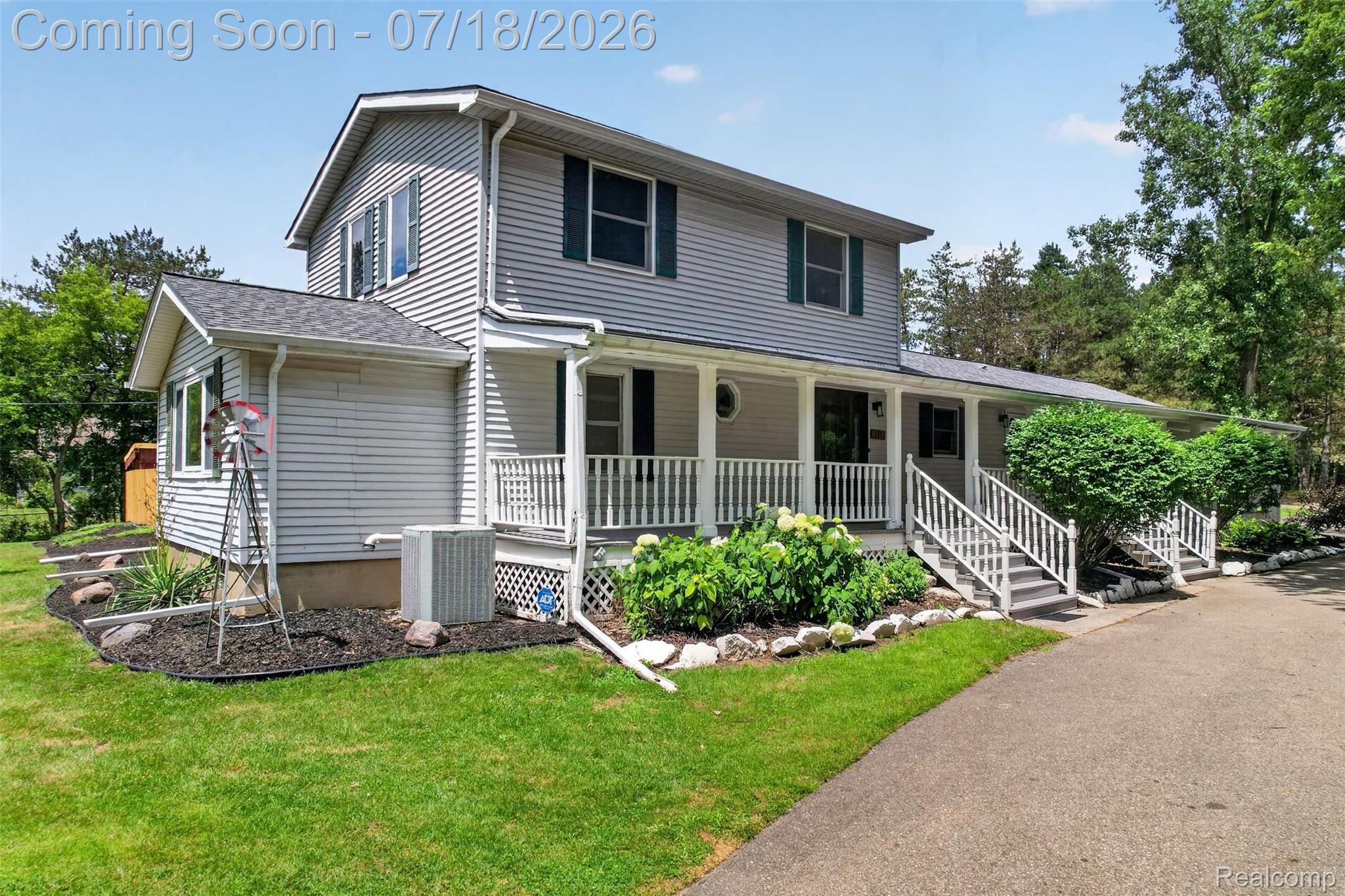 1437 East Cook Road Grand Blanc, MI 48439 - Photo 65 of 69 Two-story home with light gray siding, dark green shutters, and a covered front porch featuring white railings