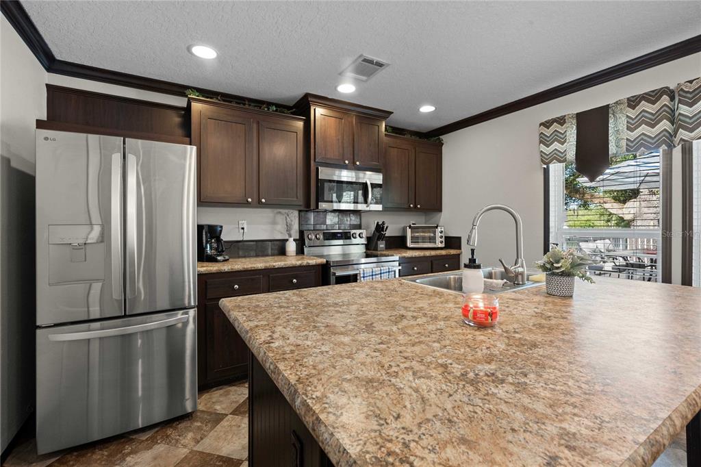 3283 Neff Lake Road Brooksville, FL 34602 - Photo 12 of 37 a kitchen with stainless steel appliances granite countertop a refrigerator a stove and a sink with wooden floor