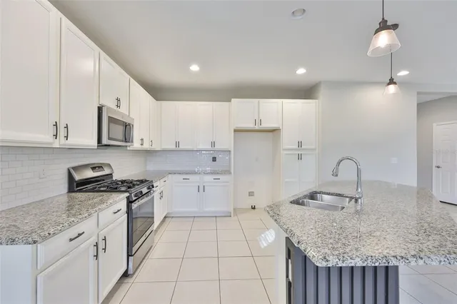 a kitchen with granite countertop a sink a stove top oven and white stainless steel appliances