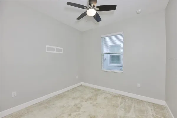 a view of an empty room and chandelier fan