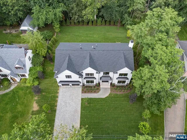 an aerial view of a house with outdoor space and trees all around