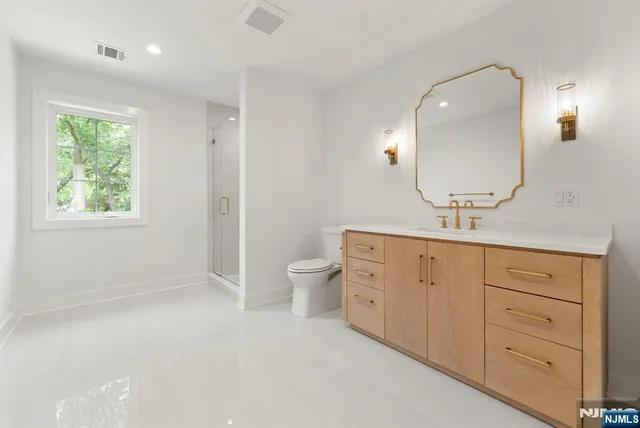 a spacious bathroom with a double vanity sink a toilet and a mirror
