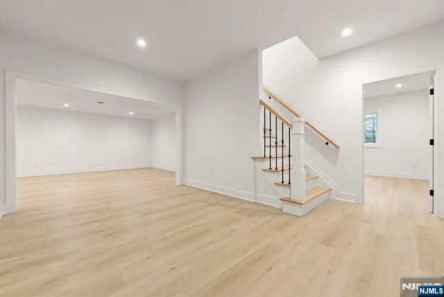 a view of an empty room with wooden floor and kitchen