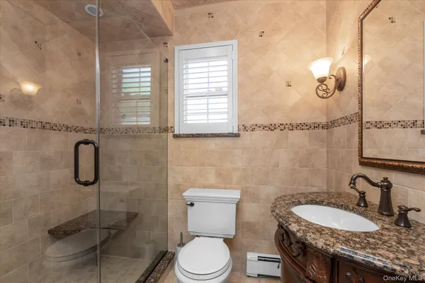 a bathroom with a granite countertop toilet sink and mirror