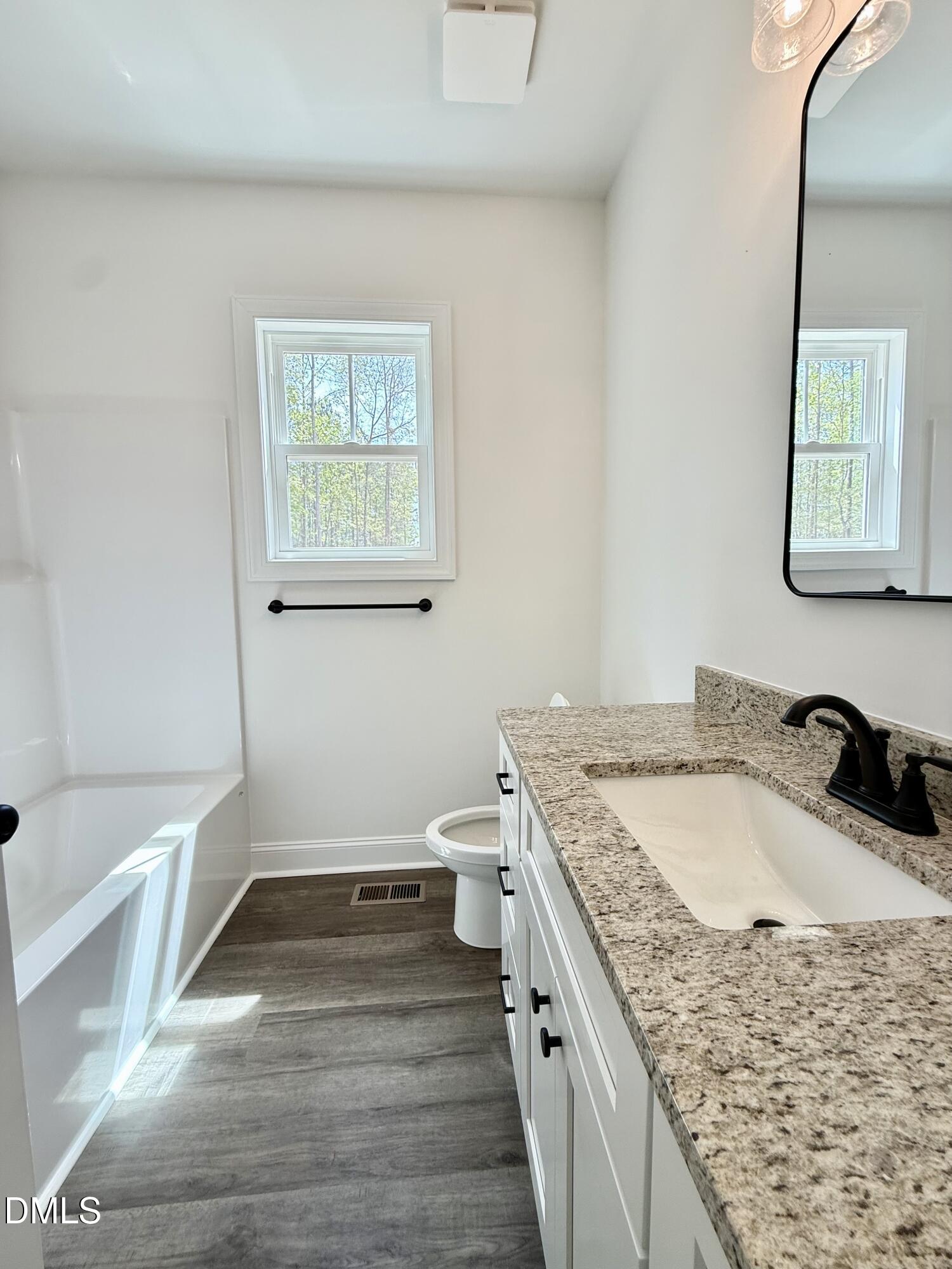 10300 Stallings Road Spring Hope, NC 27882 - Photo 7 of 36 a bathroom with a granite countertop sink a toilet a vanity and mirror