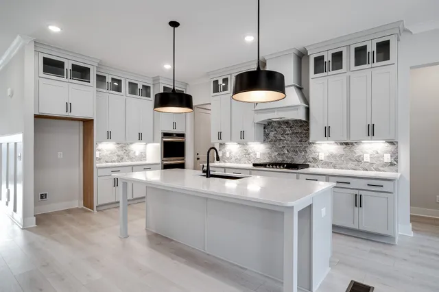 a kitchen with stainless steel appliances granite countertop a sink a stove a refrigerator and island with wooden floor