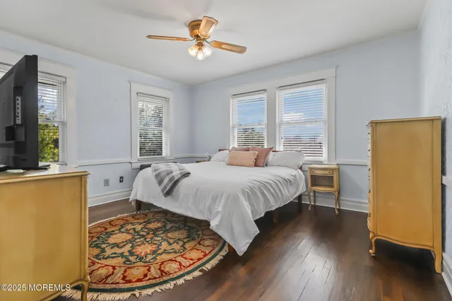 a spacious bedroom with a bed a dresser and wooden floor