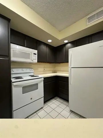 a kitchen with a refrigerator and white cabinets