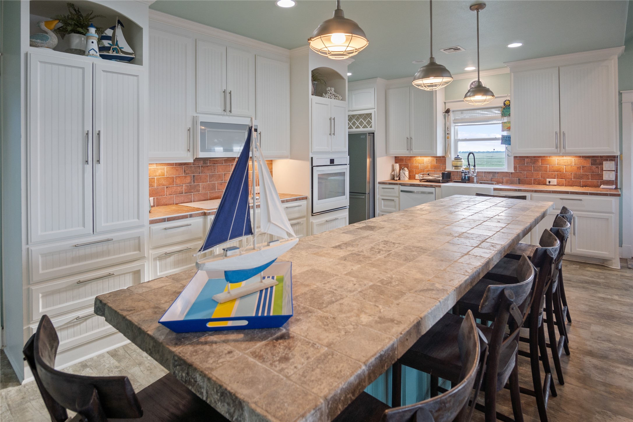 1682 Hamilton Avenue Port Bolivar, TX 77650 - Photo 16 of 38 a kitchen with stainless steel appliances kitchen island granite countertop a table chairs in it and wooden floors