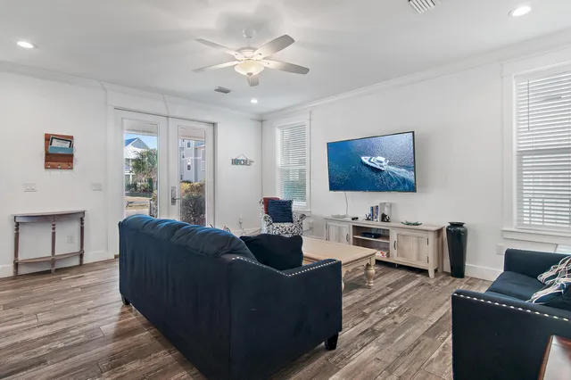 a living room with furniture a flat screen tv and wooden floor