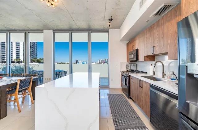 a large kitchen with stainless steel appliances kitchen island granite countertop a large kitchen island a stove a sink a refrigerator and cabinets