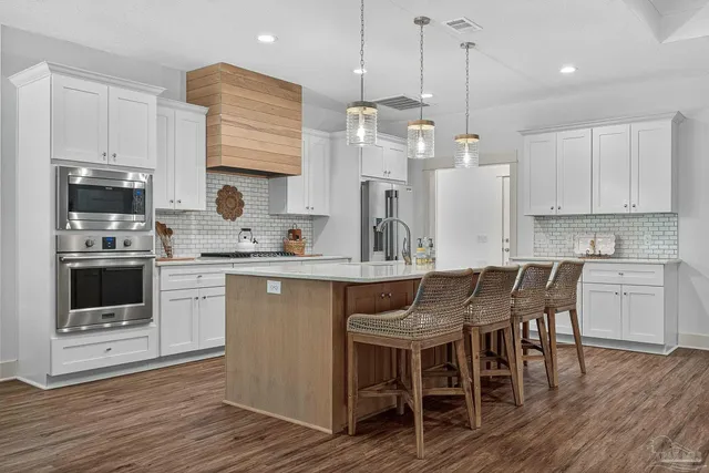 a kitchen with stainless steel appliances granite countertop a white cabinets and wooden floor