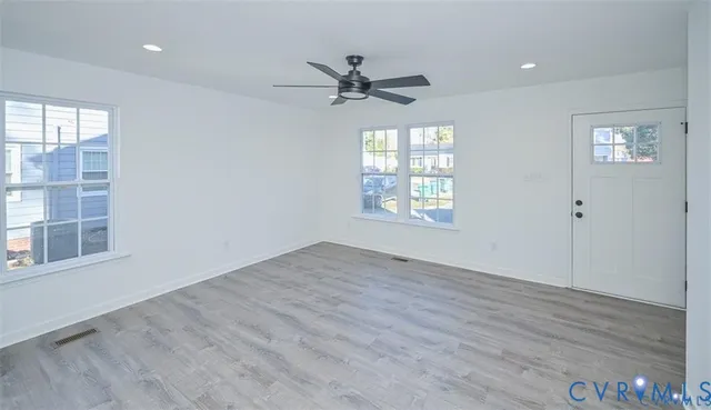 a view of an empty room with a window and wooden floor