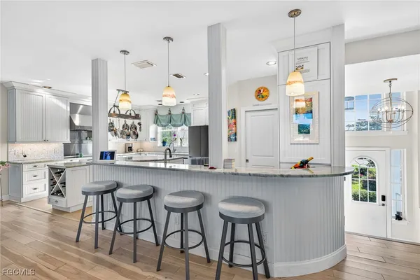 a kitchen with stainless steel appliances granite countertop a table chairs in it and wooden floors