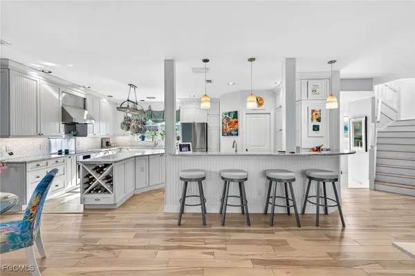 a kitchen with stainless steel appliances kitchen island granite countertop a table chairs sink and cabinets