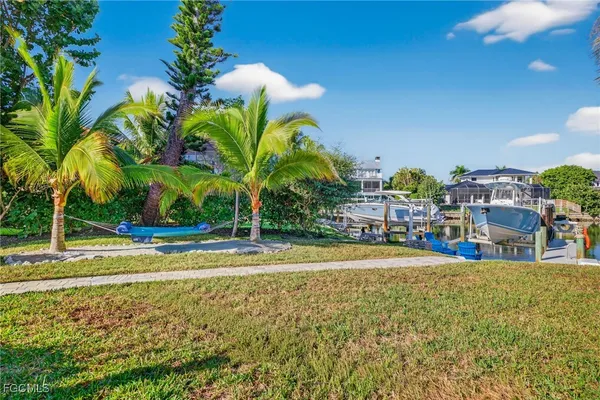 a view of a swimming pool with a yard and palm trees