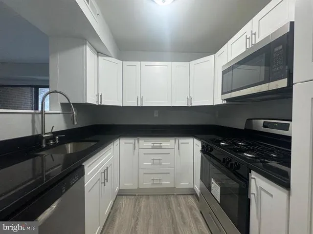 a kitchen with granite countertop white cabinets and black appliances