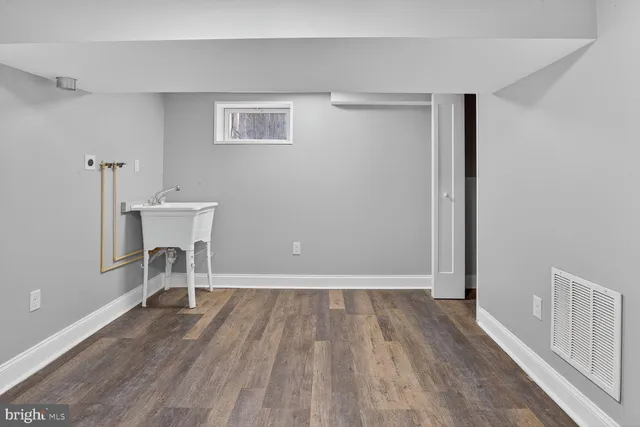 a view of a room with wooden floor white walls and windows