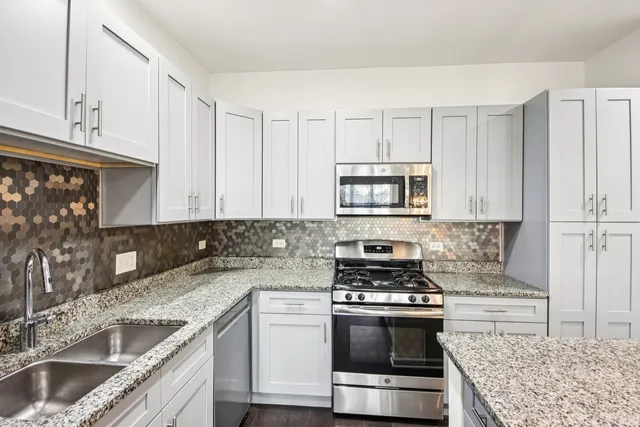a kitchen with granite countertop a stove sink and cabinets