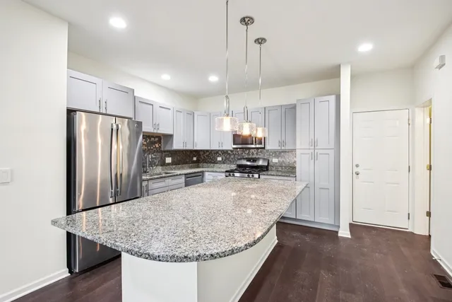 a kitchen with stainless steel appliances granite countertop a refrigerator a sink a stove a microwave and island