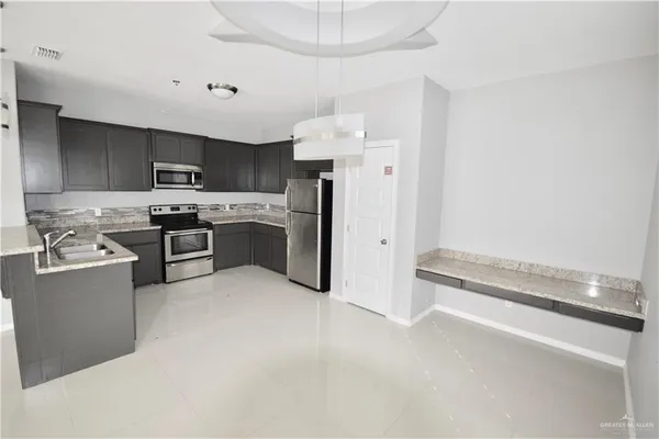 a kitchen with stainless steel appliances granite countertop a stove top oven a sink and a refrigerator