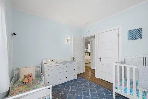 a room with baby crib and dresser