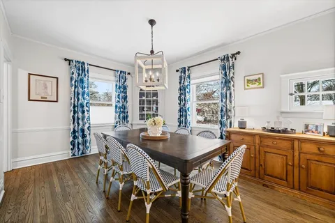 a dining room with wooden floor a chandelier a wooden table and chairs