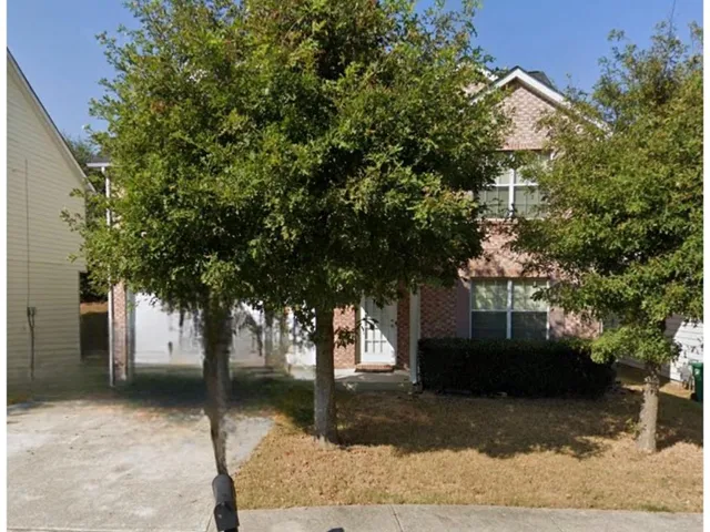 a front view of a house with a tree