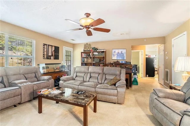 a living room with furniture ceiling fan and a large window