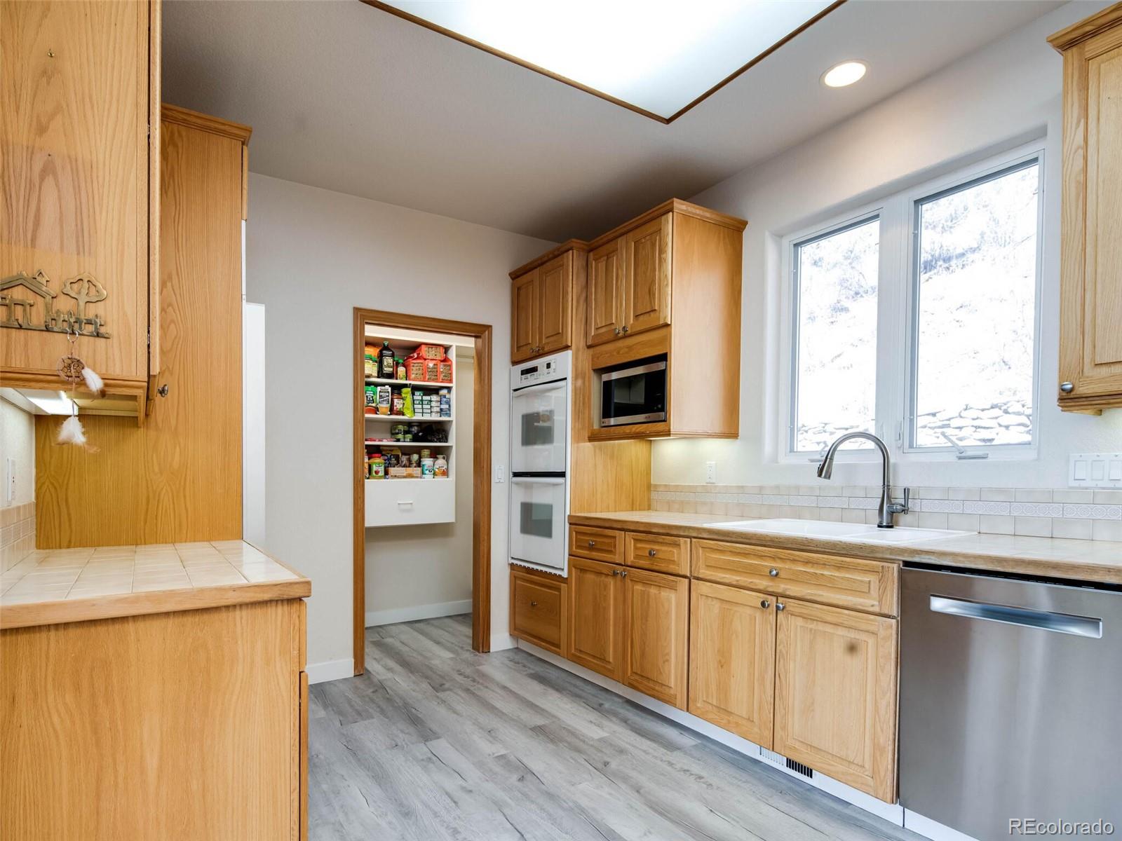 180 Nuthatch Road Evergreen, CO 80439 - Photo 11 of 40 a kitchen with stainless steel appliances white cabinets and wooden floors