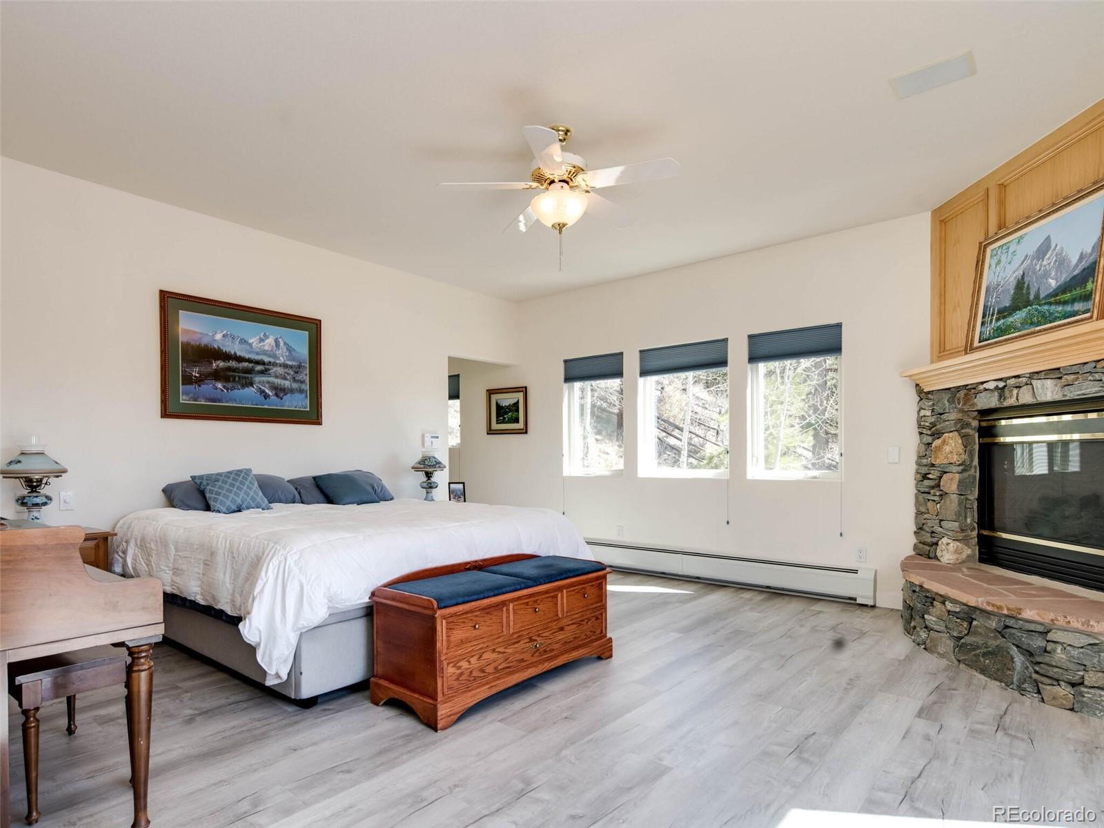 180 Nuthatch Road Evergreen, CO 80439 - Photo 21 of 40 a spacious bedroom with a bed and a fireplace