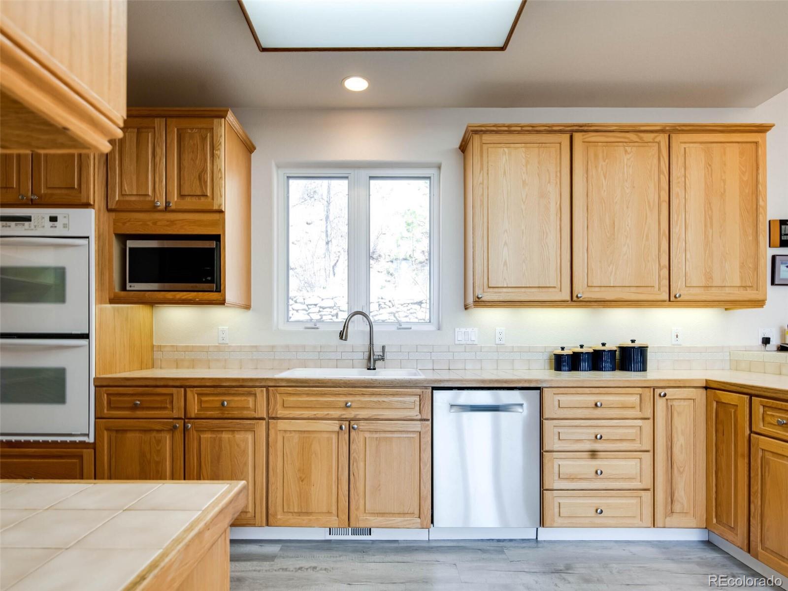 180 Nuthatch Road Evergreen, CO 80439 - Photo 10 of 40 a kitchen with stainless steel appliances granite countertop a sink and cabinets with wooden floor