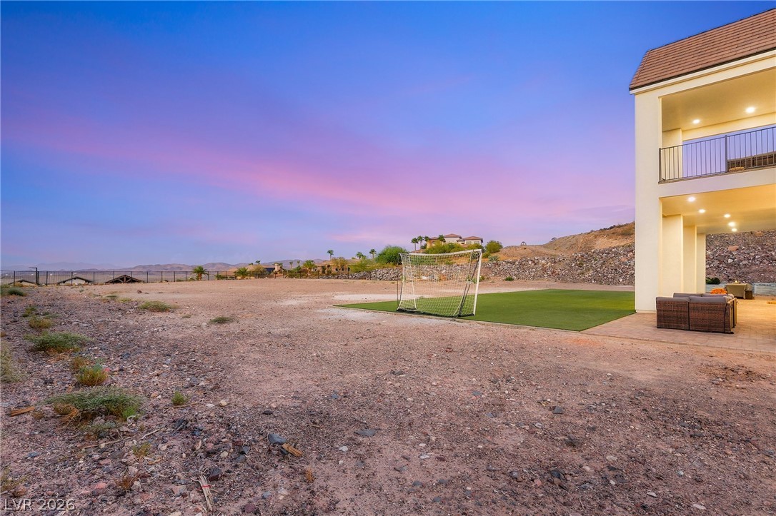 324 Wanda Road Henderson, NV 89002 - Photo 79 of 96 A spacious desert lot borders the multi-level home under a vibrant sunset sky.