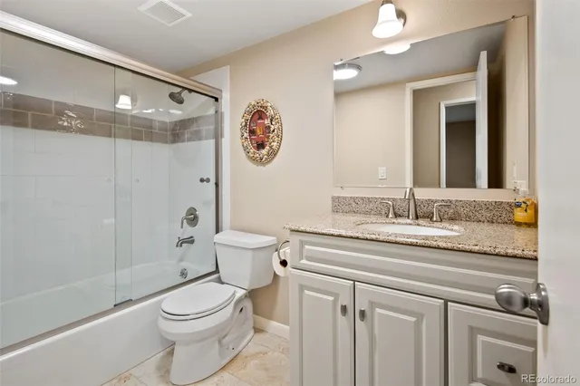 a bathroom with a granite countertop sink mirror vanity and toilet