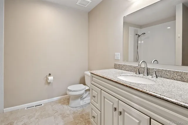 a bathroom with a granite countertop sink a toilet and a mirror