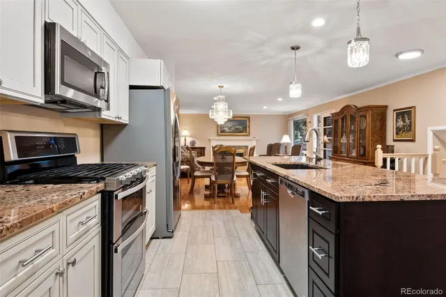 a kitchen with stainless steel appliances granite countertop a stove top oven a sink dishwasher a dining table and chairs with wooden floors