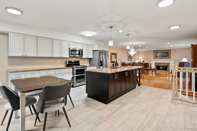 a kitchen with stainless steel appliances kitchen island granite countertop a stove top oven a sink a dining table and chairs