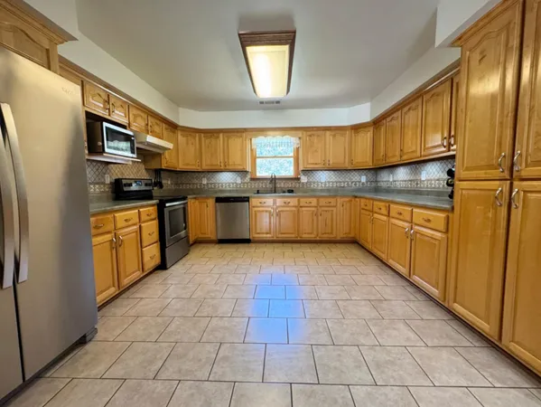 a kitchen with granite countertop a sink counter top space cabinets and stainless steel appliances