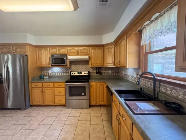 a kitchen with stainless steel appliances granite countertop a stove a sink and a refrigerator