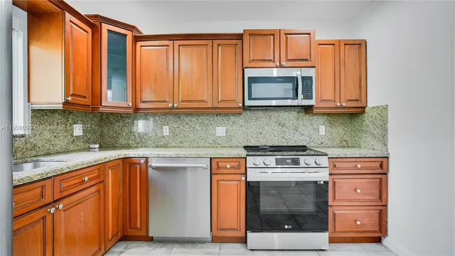 a kitchen with stainless steel appliances granite countertop a stove a sink and a microwave